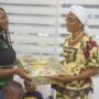A staff of Uniliver presenting a hamper to a mother at church