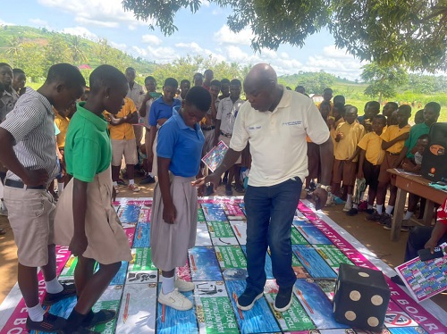 • Mr Baabu demonstrating to some school children how the board game is played