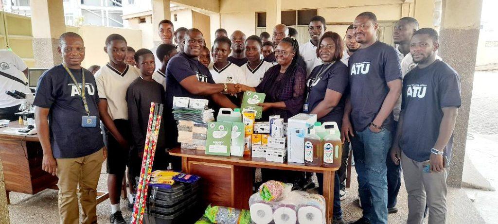 Mrs Felicity Yankson [fouth from right] receiving the items from Mr. Kojo Ayittey a Lecturer  with  the Staff of ATU and students of St John SHS.